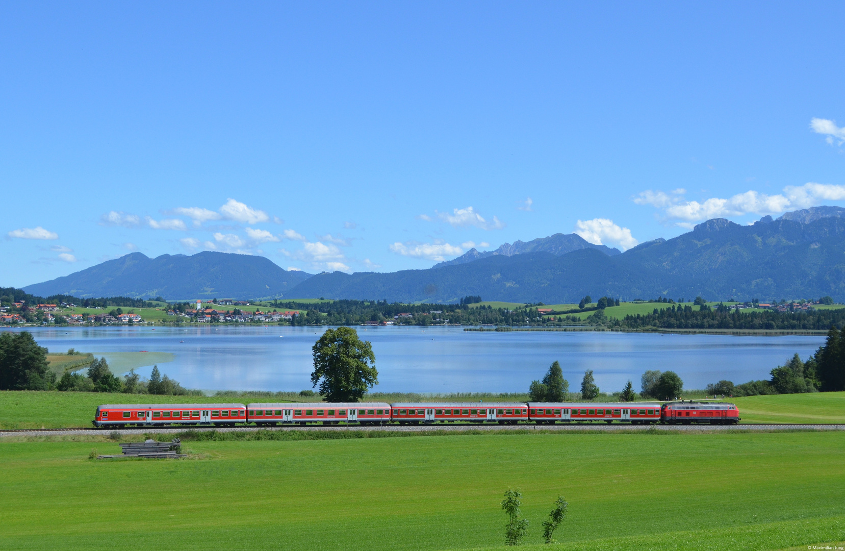 218 489 mit ihrer Regionalbahn nach Füssen vor dem Hopfensee bei Hopferau