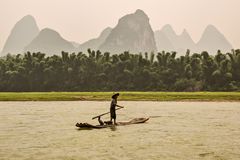 437 - Yangshuo - Fisherman on Bamboo Raft with his Cormorant. On Background the Karst Peaks