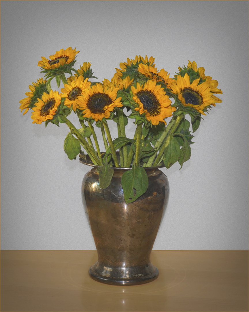 A bouquet of sunflowers in a silver vase