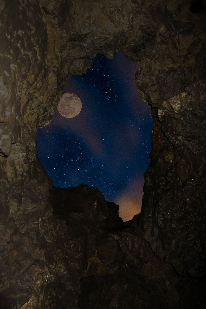 a cave, the moon and a sky full of stars