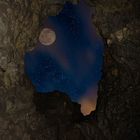 a cave, the moon and a sky full of stars