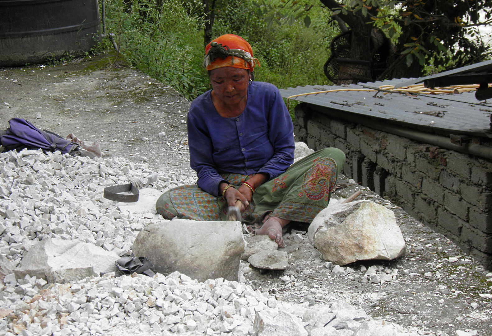 A GARHWAL WOMAN BREAKING STONES