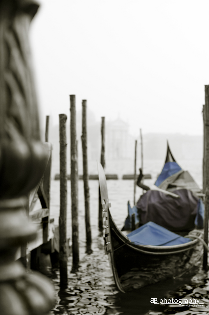 A Venetian gondola and San Giorgio Maggiore in the background hidden by the fog