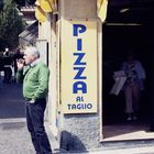 Älterer Herr vor einem Pizzaladen