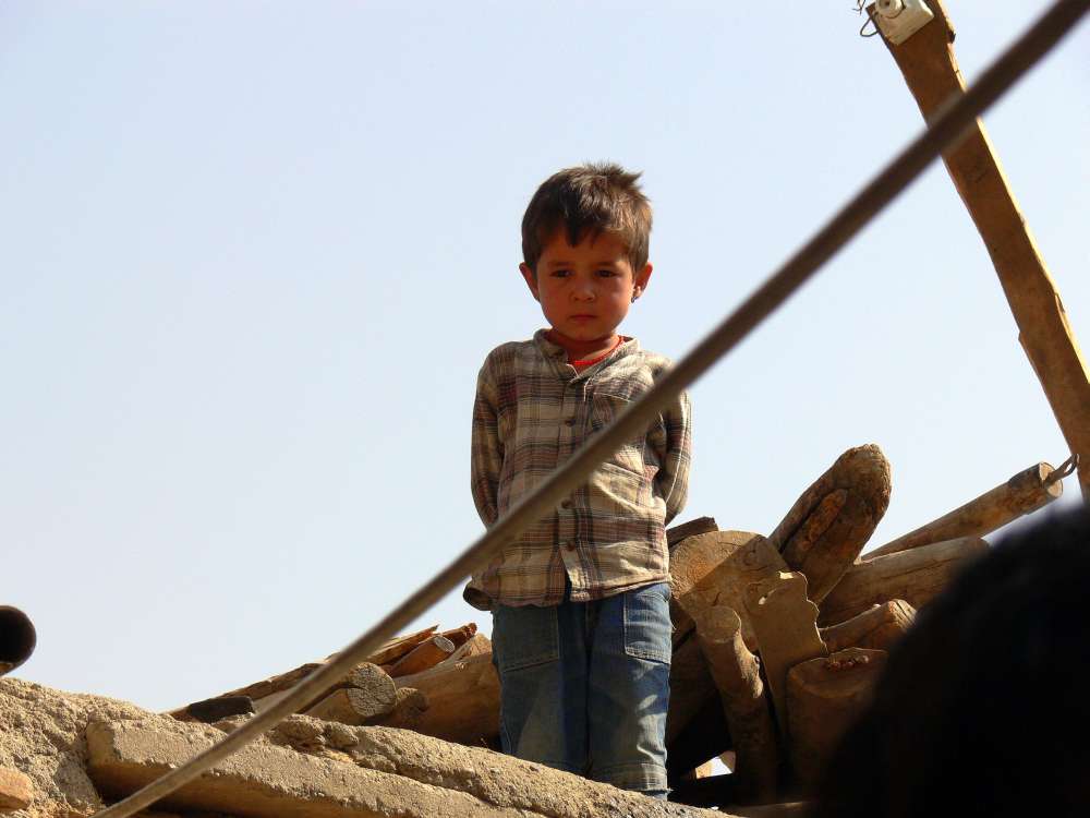 Afghanischer Junge auf den Trümmern des Hauses seiner Eltern