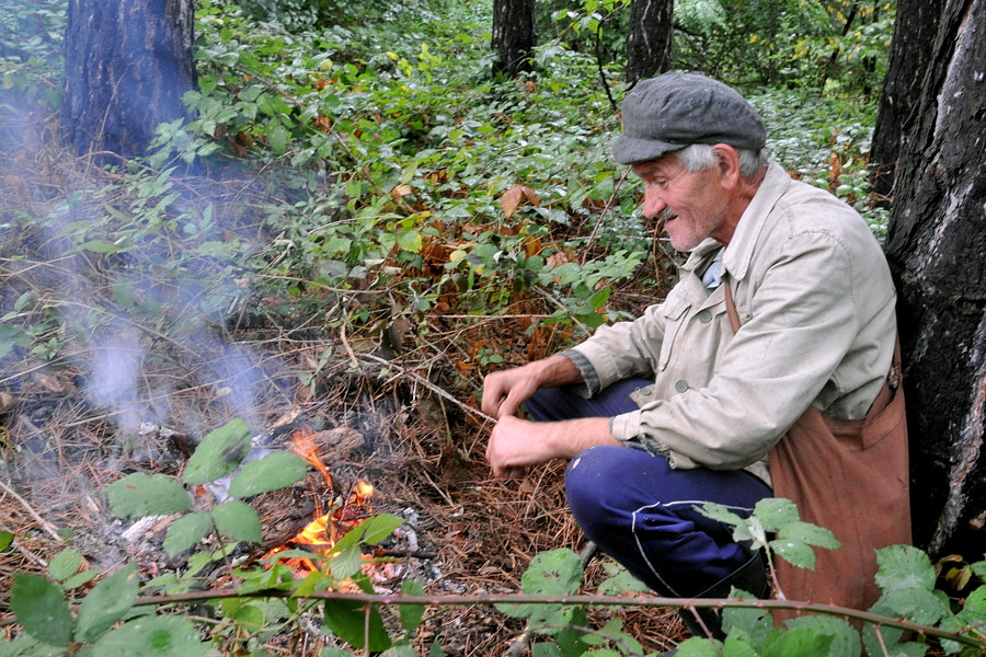 Allein im Wald, im Regen, ein Hirte wärmt sich am Feuer