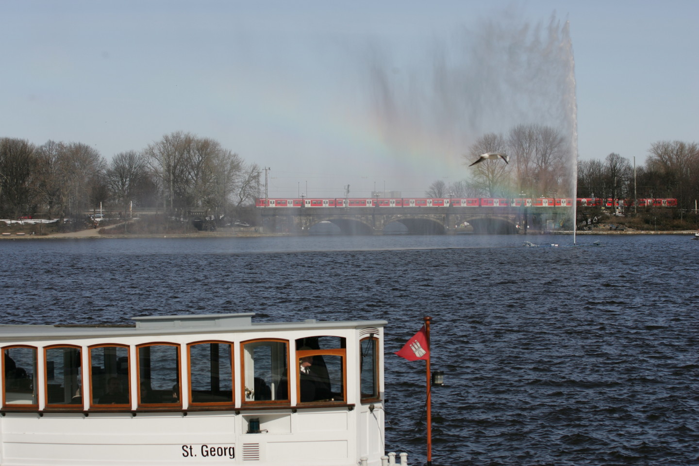 Alsterfontäne mit Regenbogen, Möwe, S-Bahn und Schiff