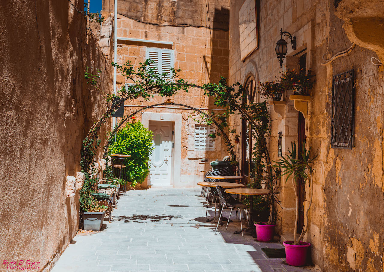 Alte Gasse im alten Stadt von Mosta, Café-Tisch und Pflanzgefäße