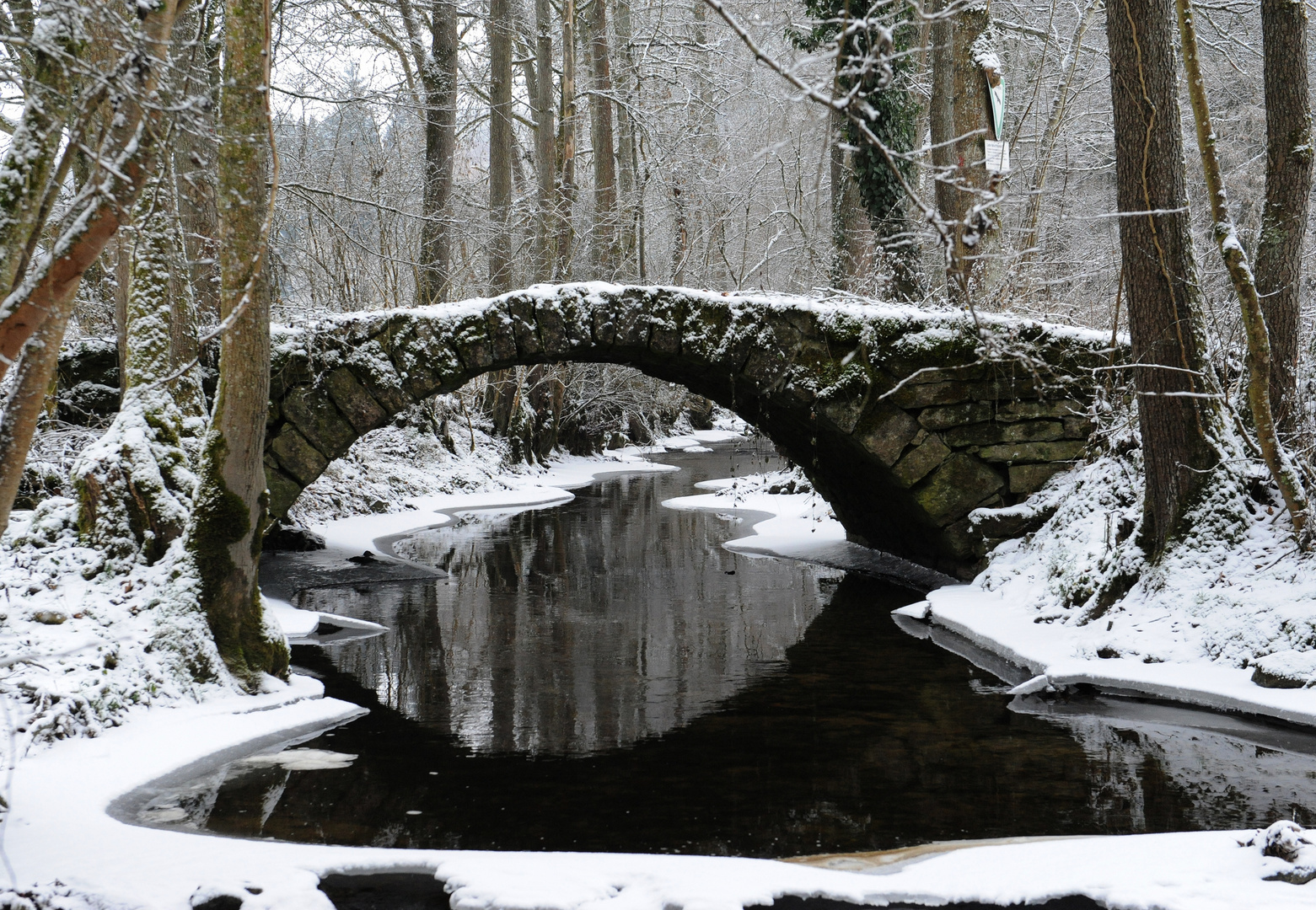 Alte Steinbrücke über den Bach im Winter