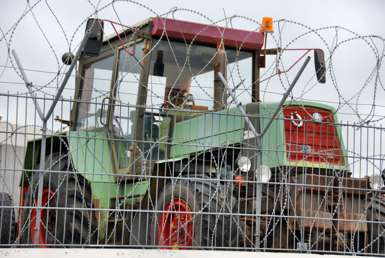 Alter Traktor hinter Stacheldraht