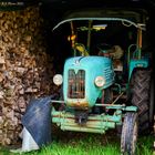 Alter Traktor versteckt in Holzstapeln am Mühlenwanderweg