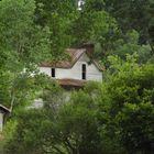 Altes Landhaus von Bäumen umgeben.