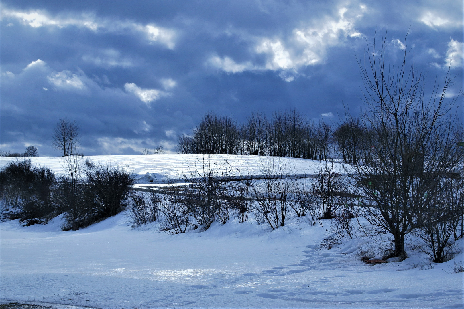 Altschnee glänzt unter den Wolken