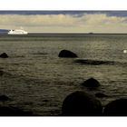 Am grauen Strand am grauen Meer und weitab fährt ein Schiff