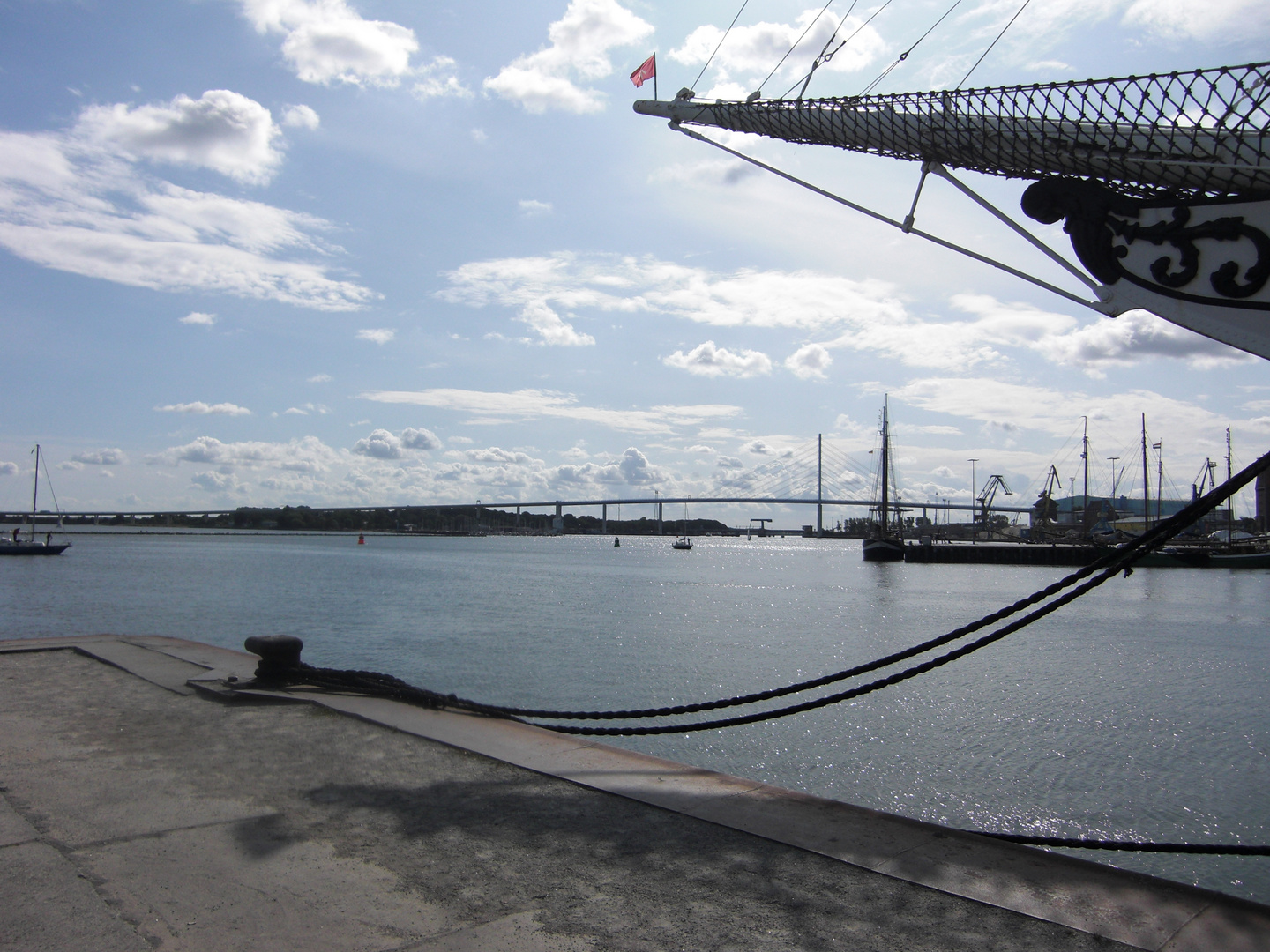 Am Hafen - Im Hintergrund neue, über 4000 m lange Rügenbrücke - vorn Bug von Gorch Fock