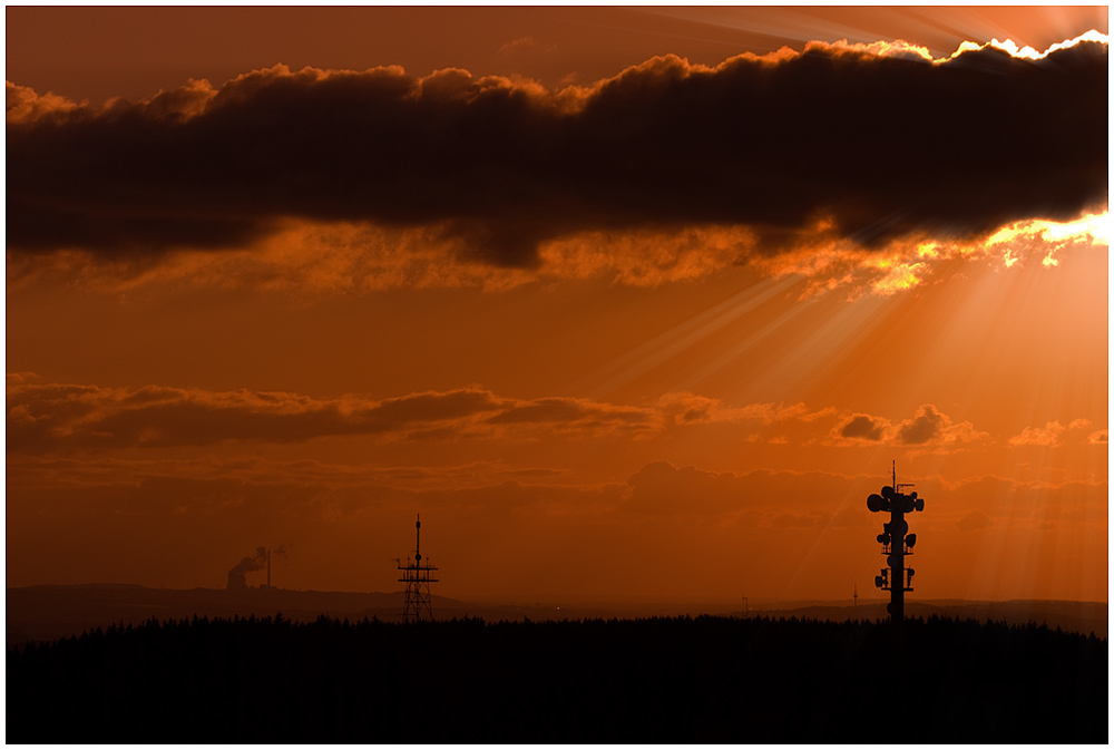 artifical sunrays bursting through cloud in a scenery with a lot of towers creating an orange soup