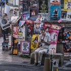 assis sur un banc en pierre, dos au mur, les yeux sur un écran, l'homme portait des chaussettes