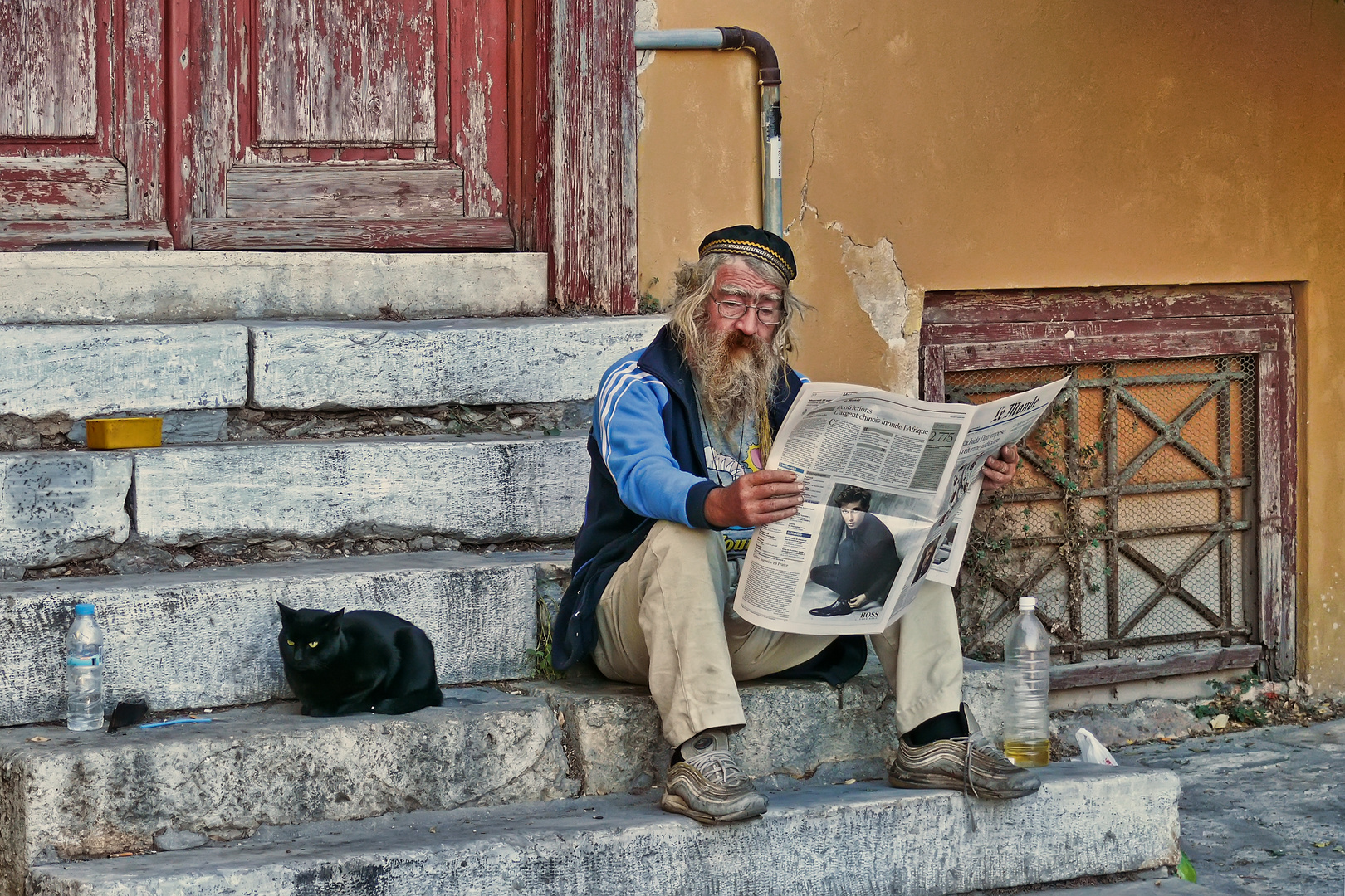 Athen_Mann in der Plaka liest auf Trepp die Le Monde