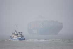 Aus dem Nebel kommt ein Containerschiff