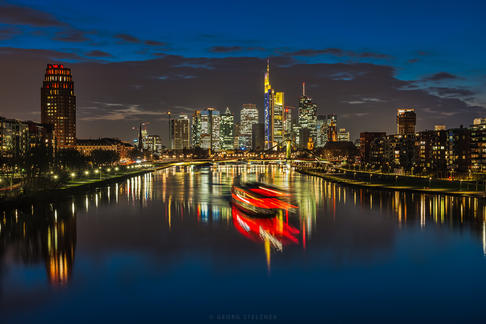 Ausflugsdampfer vor der Skyline von Frankfurt zur blauen Stunde