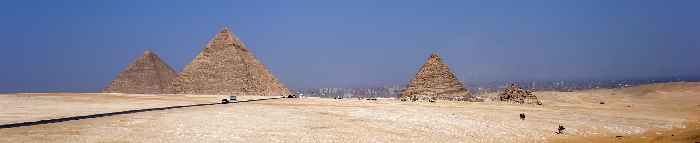 Autos, Busse, Pferde, Kamele,eine Straße, ein paar Pyramiden und Kairo im Dunst