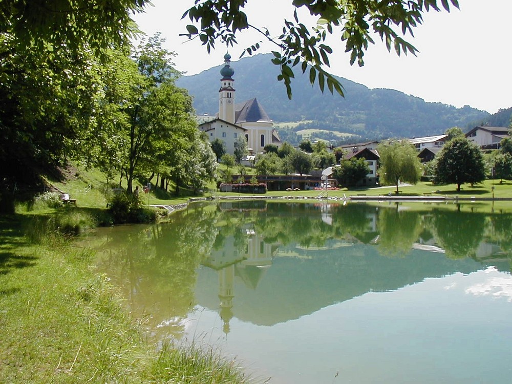 Badesee und Kirche in Reith im Alpbachtal in Tirol