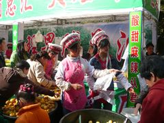 Bai-Maedchen verkaufen Mirabellen auf dem Fruehlingsfestmarkt in Kunming