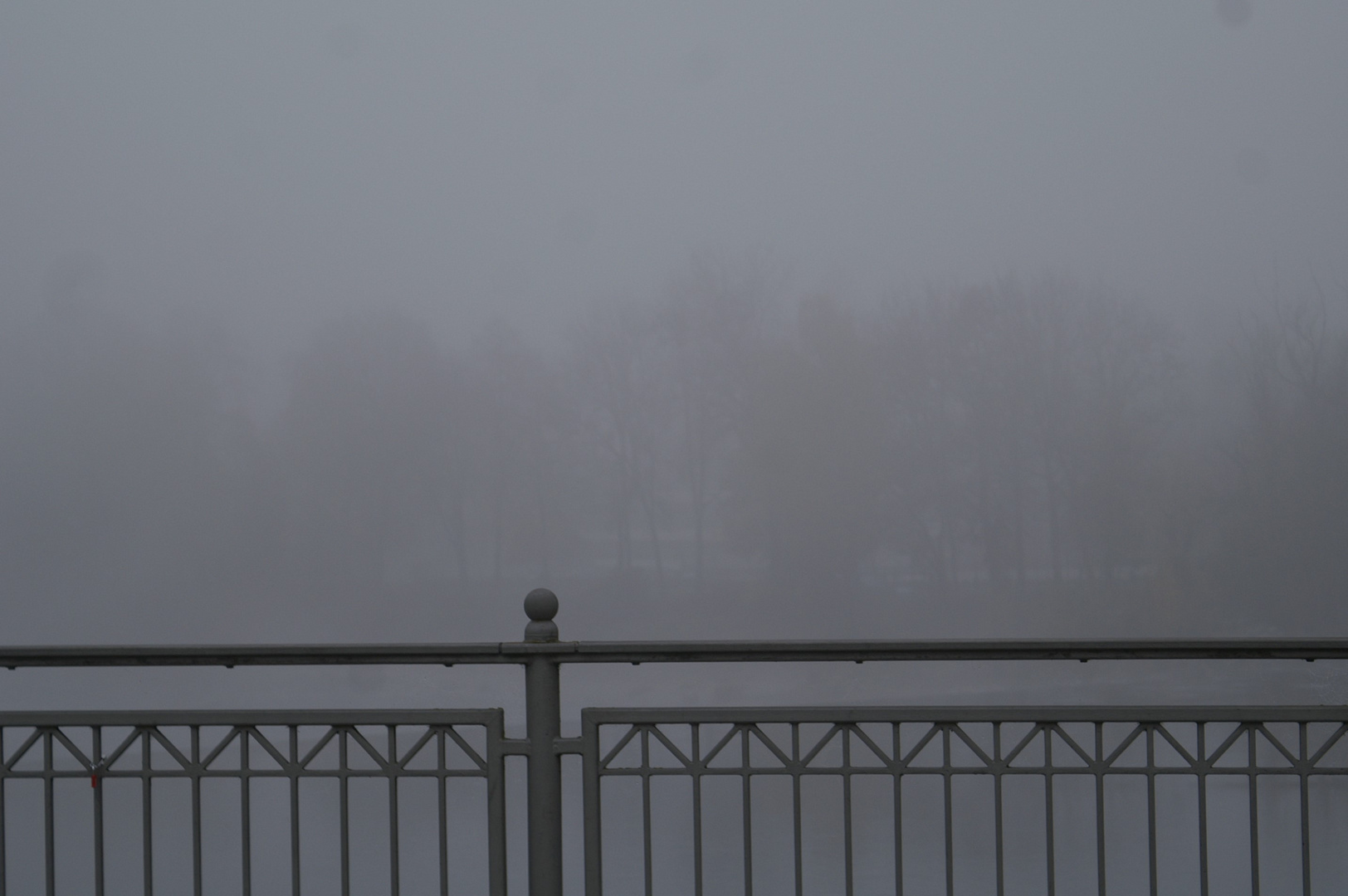 Balustrade im Nebel mit Bäumen im Hintergrund