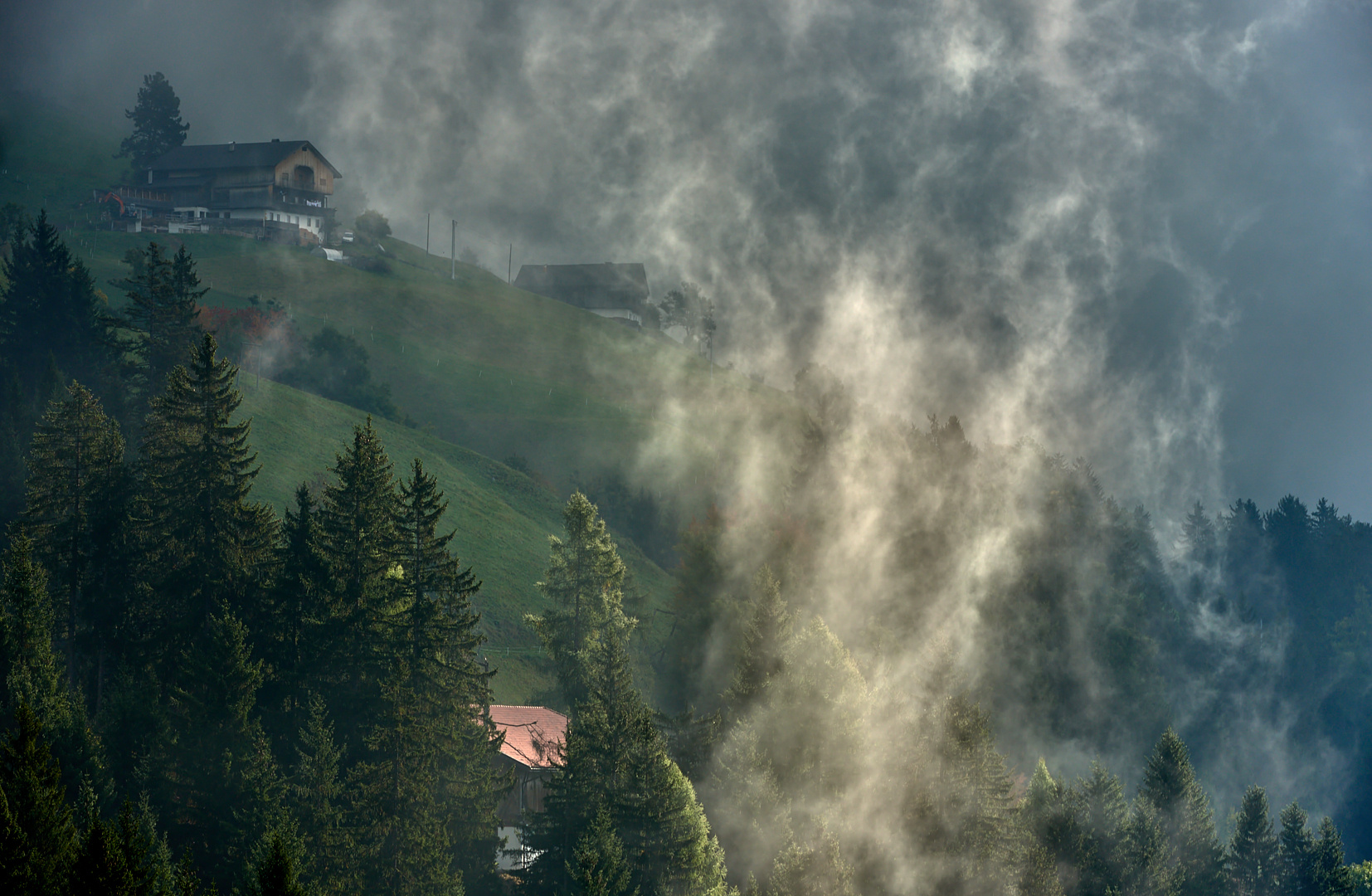 Bauernhöfe auf 1400 m Höhe im Pustertal mit Licht-Nebelstimmung beim Sonnenaufgang.