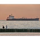 Beach walkers and tanker at sunset (the Idylic Nordsea)