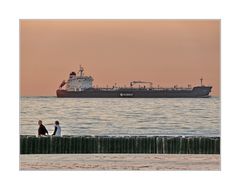 Beach walkers and tanker at sunset (the Idylic Nordsea)