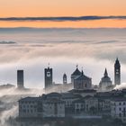 Bergamo Alta emerge sopra un mare di nuvole.