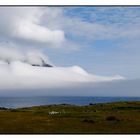 Bild mit kleinem Leuchtturm und einem Berg fast vollständig von Wolken eingehüllt