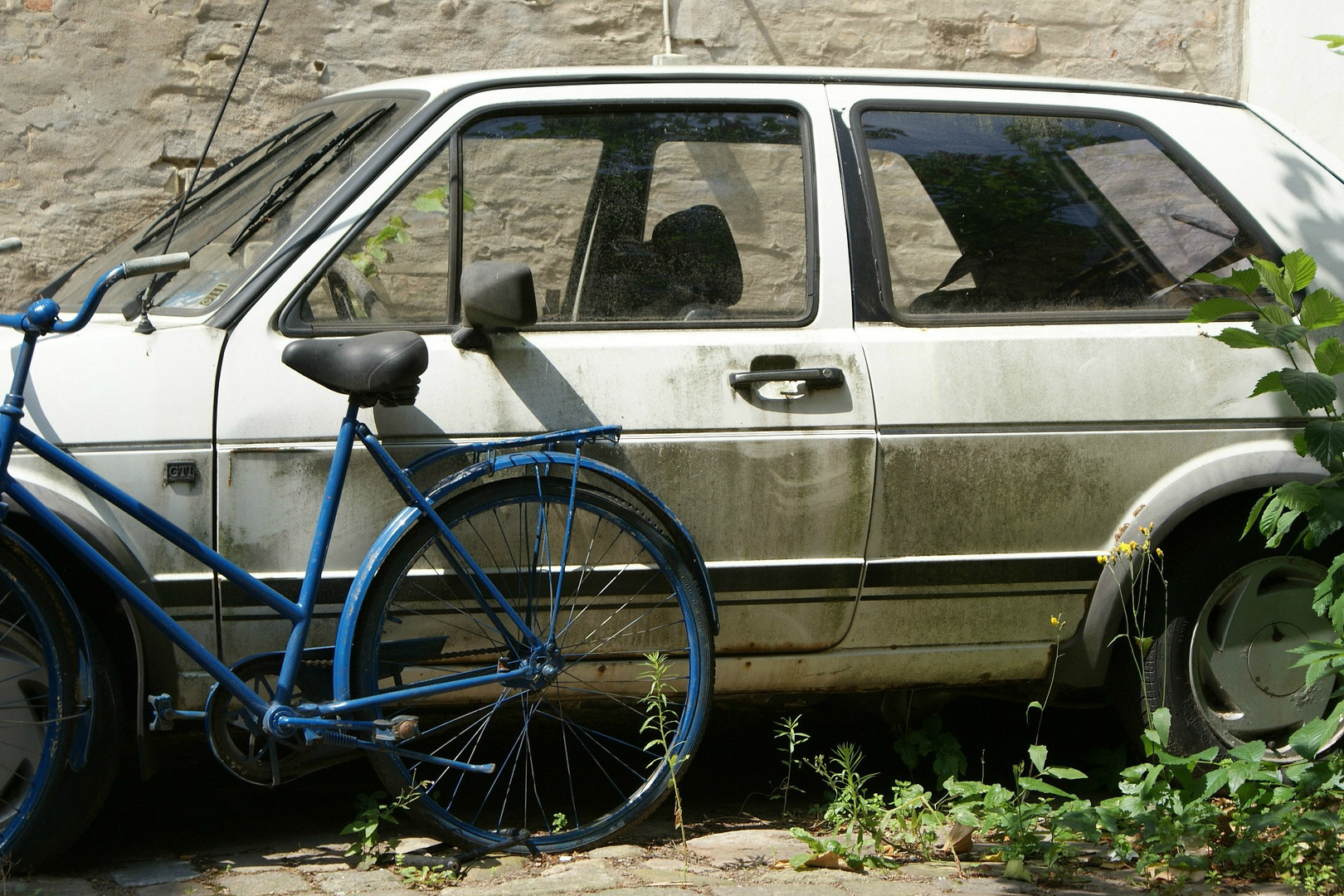 Blå cykel framför vit bil