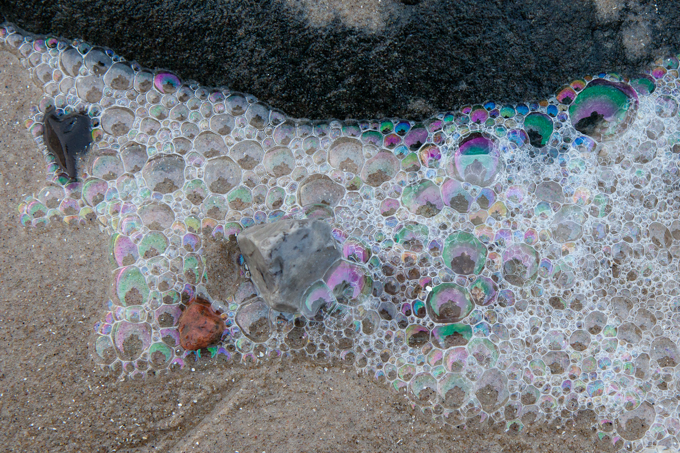 Blasen auf Sand mit schwarzem Stein
