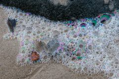 Blasen auf Sand mit schwarzem Stein