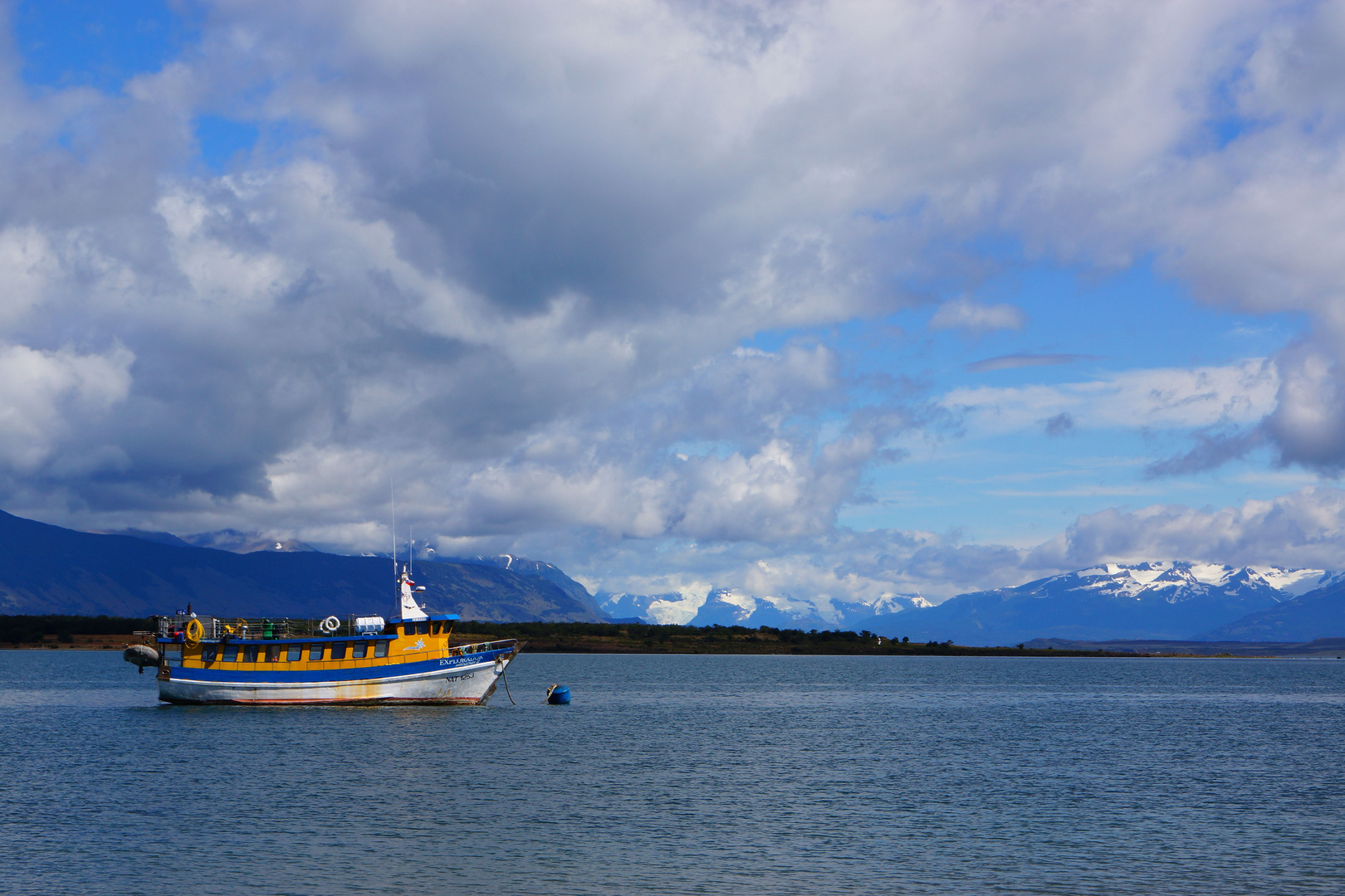 blau gelbes Schiff vor schneebedeckten Bergen