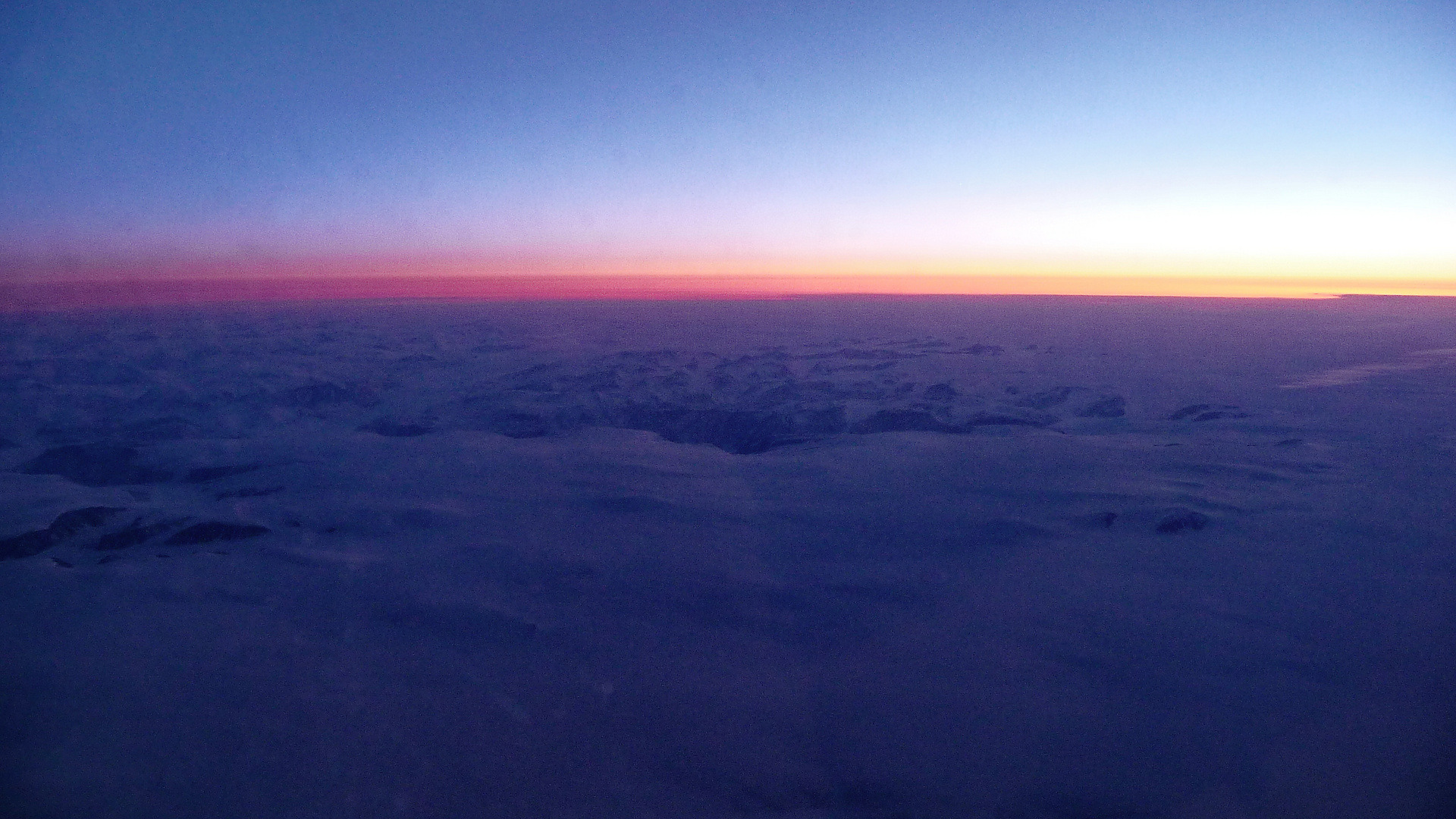 Blaue Stunde über Grönland aus dem Flugzeugfenster