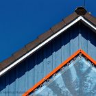 BLAUER GIEBEL MIT PIEPSER UNTER BLAUEM HIMMEL