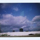 blauer Himmel über Industrielandschaft aus dem fahrenden Auto auf der Autobahn