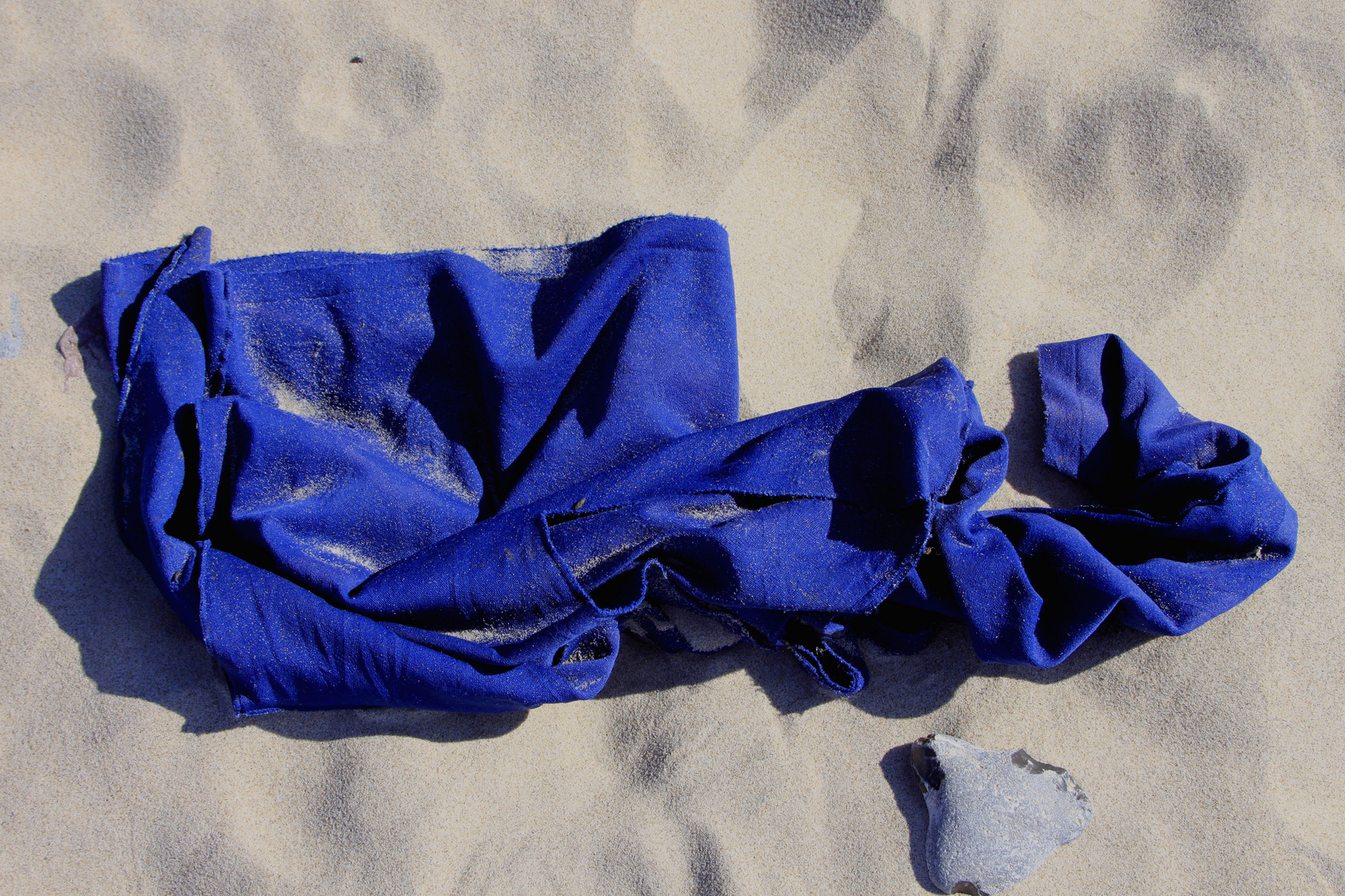 blauer Stoff mit Stein auf Sand