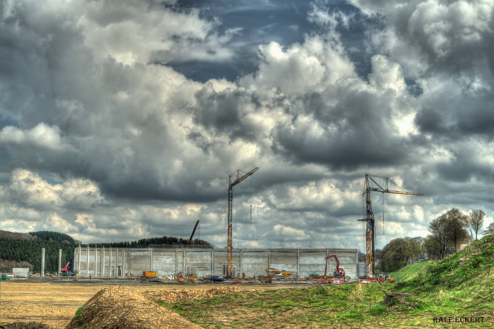 Blick auf eine Baustelle mit zei Kränen und einem Rohbau in Farbe