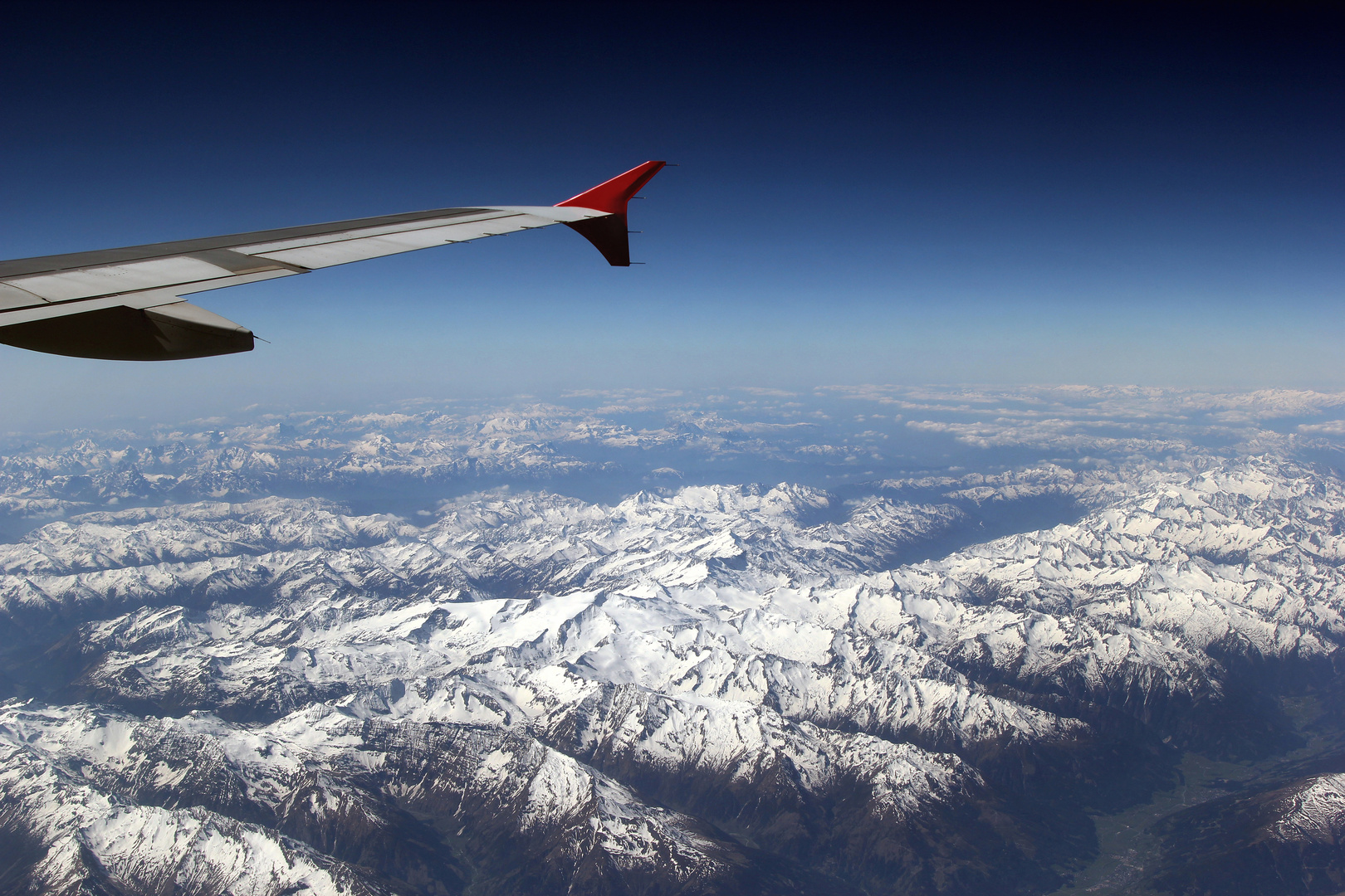 Blick aus dem Flugzeugfenster auf die schneebedeckten österreichischen Alpen