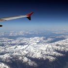 Blick aus dem Flugzeugfenster auf die schneebedeckten österreichischen Alpen