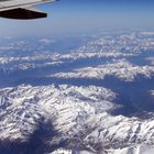 Blick aus dem Flugzeugfenster auf die vom Schnee bedeckten österreichischen Alpen