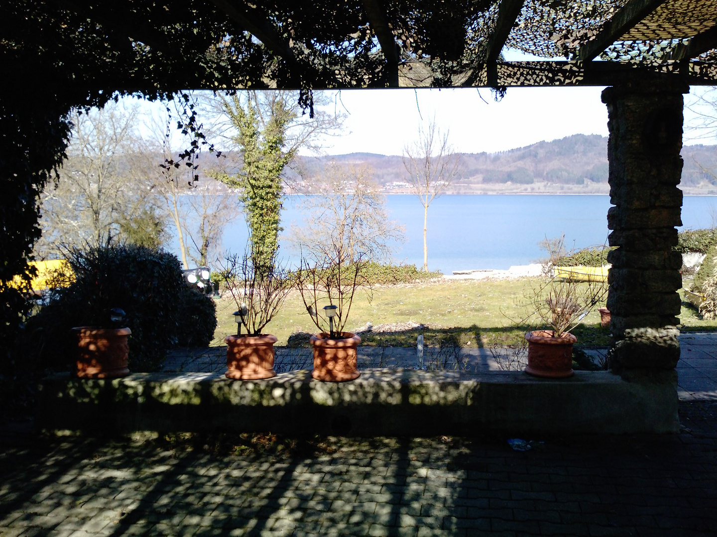 Blick aus der schattigen Laube auf den blauen Bodensee