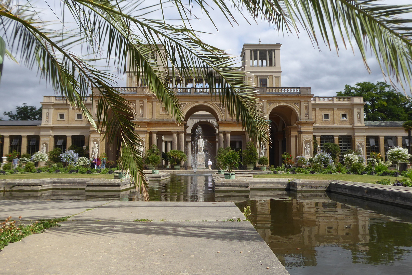 Blick durch die riesige Palme auf die Orangerie