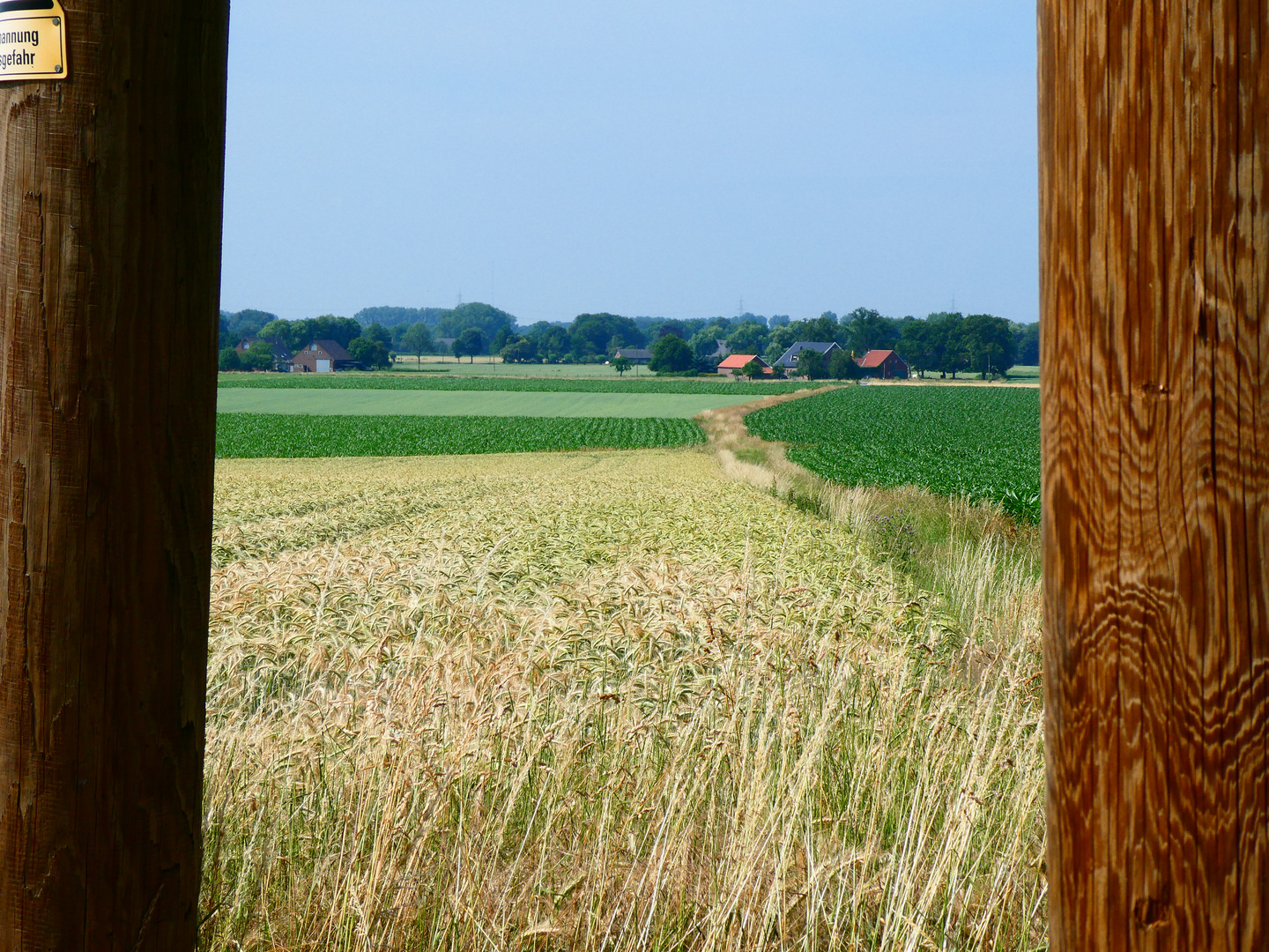 Blick durch einen Strommast auf dem Land