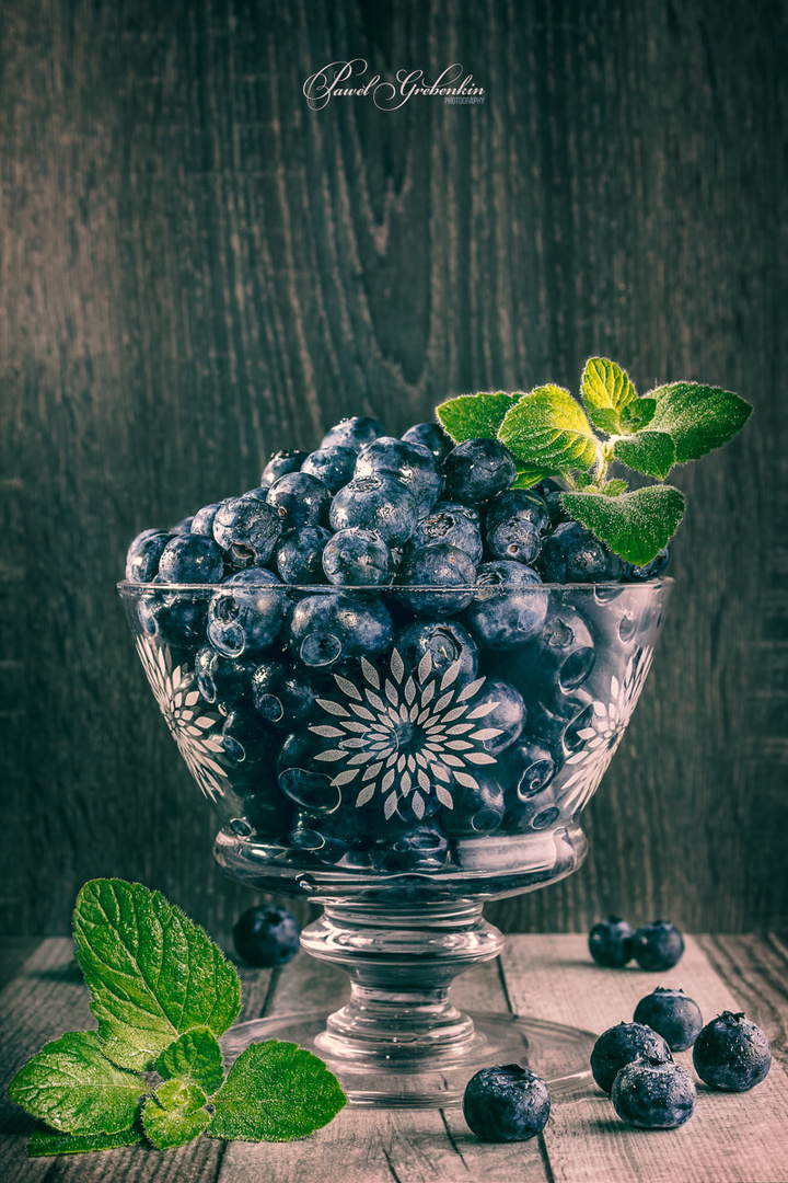 Blueberries in a glass vase with mint leafs