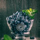 Blueberries in a glass vase with mint leafs